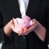 Business woman holding a broken piggy bank