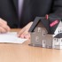 Businessman signs contract behind household architectural model