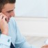 Young business man at office desk using cellphone and holding pa