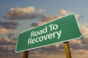 Road To Recovery Green Road Sign with dramatic clouds and sky.